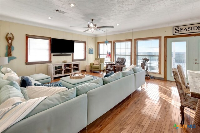 living room with light wood-type flooring, french doors, ceiling fan, and crown molding