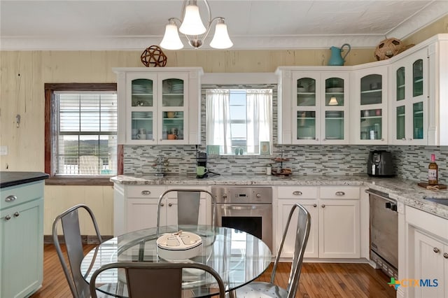 kitchen featuring stainless steel appliances, a wealth of natural light, decorative light fixtures, and light stone countertops