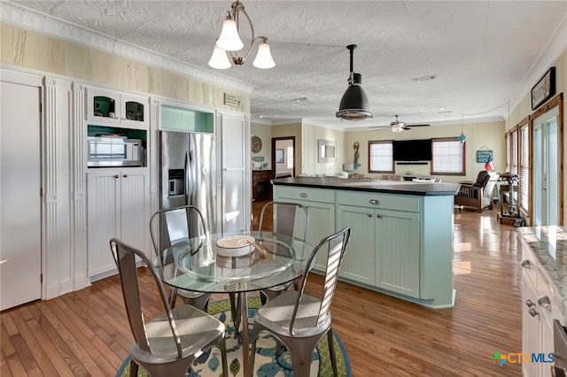 dining area featuring hardwood / wood-style floors, ceiling fan with notable chandelier, and a textured ceiling