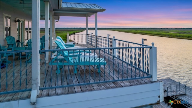 deck at dusk featuring a water view