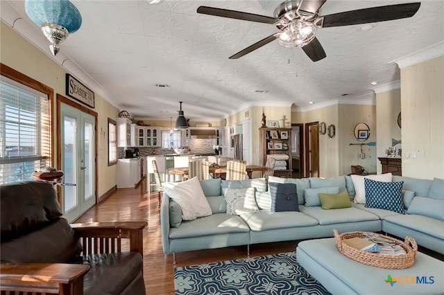 living room with hardwood / wood-style flooring, ceiling fan, and crown molding