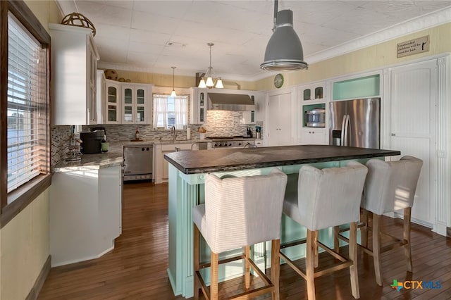 kitchen with stainless steel appliances, dark hardwood / wood-style flooring, hanging light fixtures, a kitchen breakfast bar, and white cabinets