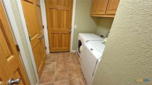 washroom featuring washing machine and dryer, cabinets, and light tile patterned flooring