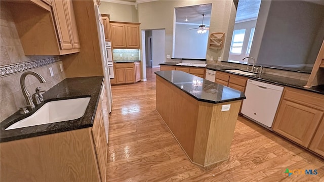 kitchen with ornamental molding, white appliances, sink, and a center island