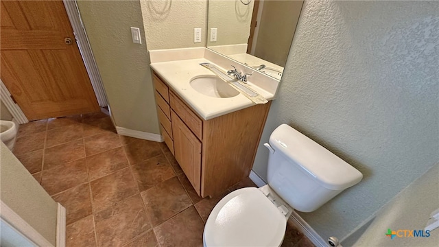 bathroom with toilet, vanity, and tile patterned floors