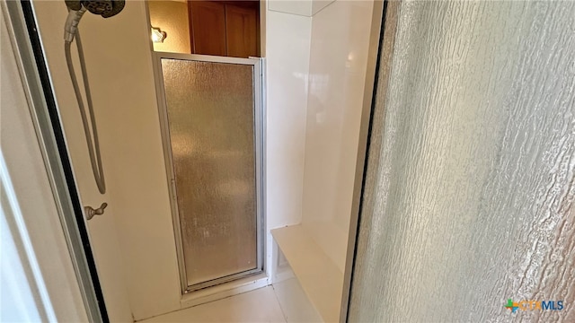 bathroom with a shower with shower door and tile patterned flooring