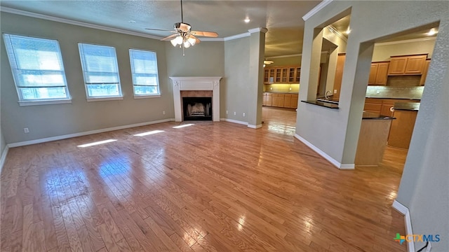 unfurnished living room featuring light wood-type flooring, a healthy amount of sunlight, and ceiling fan