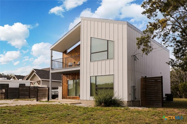 back of property with a yard, a balcony, and central air condition unit