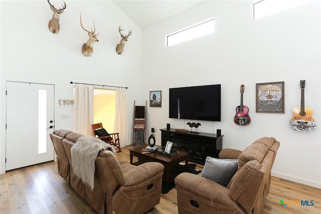 living room featuring a fireplace, light wood-type flooring, and high vaulted ceiling