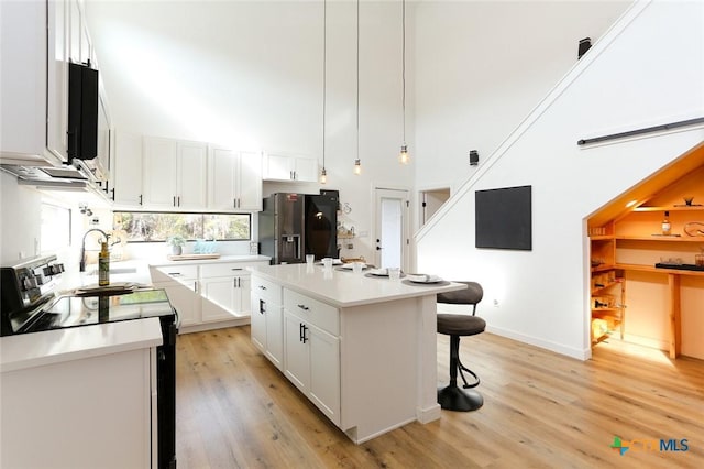 kitchen featuring white cabinets, stainless steel fridge, electric range, and a kitchen island