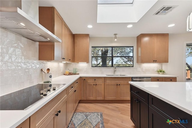 kitchen featuring wall chimney range hood, visible vents, a sink, black electric stovetop, and backsplash