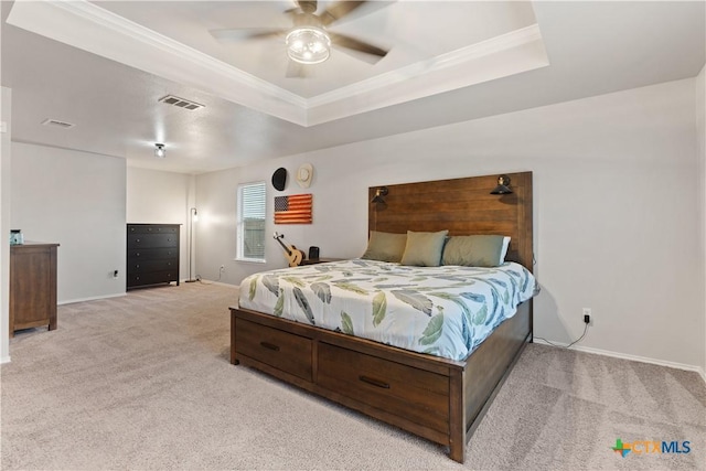 bedroom featuring crown molding, a raised ceiling, and light carpet