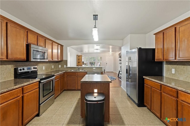 kitchen featuring sink, a center island, appliances with stainless steel finishes, pendant lighting, and backsplash