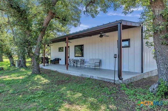 rear view of property featuring a lawn, ceiling fan, and a patio area