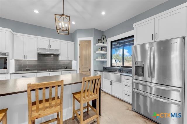 kitchen featuring sink, stainless steel appliances, tasteful backsplash, pendant lighting, and white cabinets