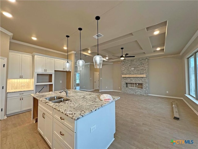 kitchen featuring coffered ceiling, white cabinetry, sink, and a kitchen island with sink