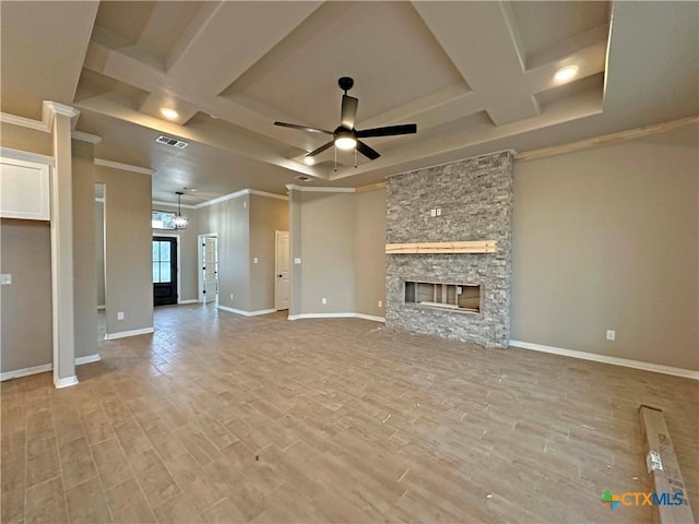 unfurnished living room with a stone fireplace, ornamental molding, coffered ceiling, ceiling fan, and light hardwood / wood-style floors