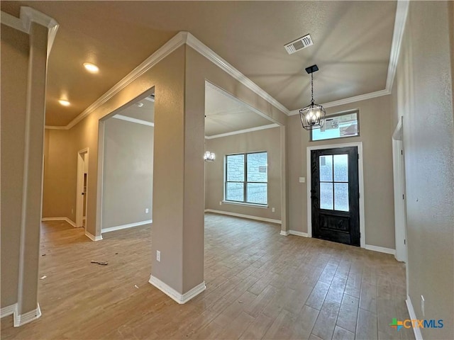 entryway with hardwood / wood-style flooring, crown molding, and a chandelier