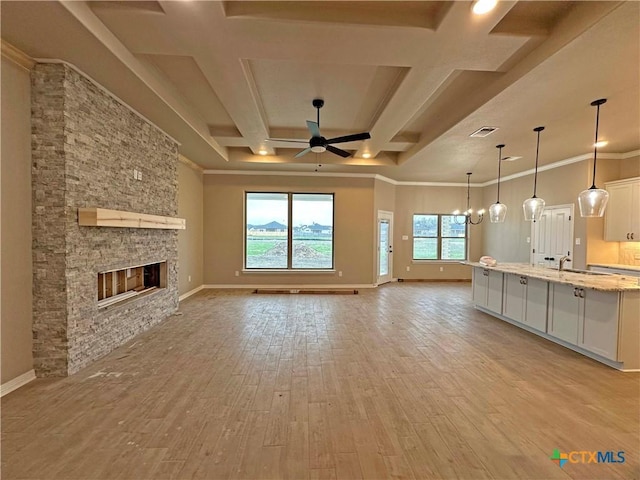 unfurnished living room with crown molding, ceiling fan, a fireplace, and light hardwood / wood-style flooring