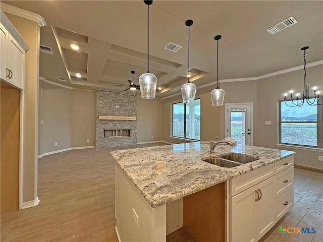 kitchen featuring white cabinetry, sink, a kitchen island with sink, and a fireplace