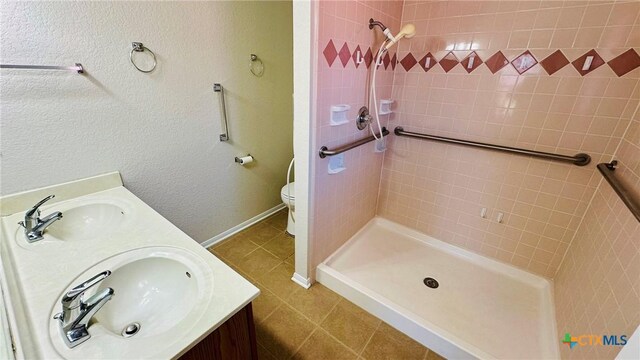 bathroom with double vanity, tile patterned flooring, toilet, and a sink