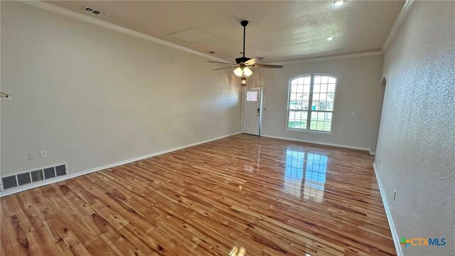 interior space featuring baseboards, arched walkways, ceiling fan, wood finished floors, and crown molding