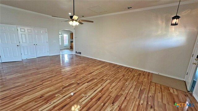 interior space featuring baseboards, arched walkways, a ceiling fan, dark wood-style floors, and ornamental molding