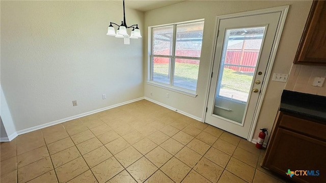 unfurnished dining area featuring baseboards and a notable chandelier