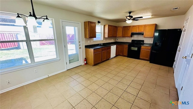 kitchen with under cabinet range hood, a sink, black appliances, brown cabinetry, and dark countertops