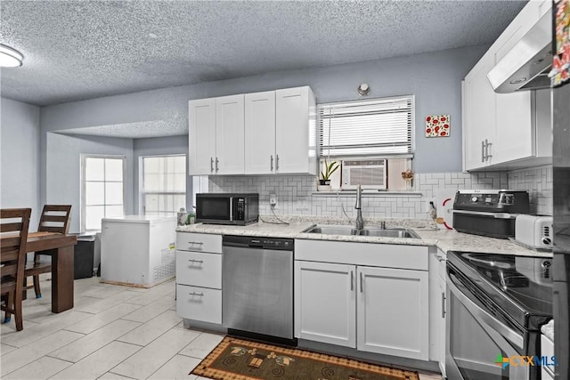 1003 Tyler Dr, Copperas Cove, TX 76522 - kitchen with stainless steel appliances, ventilation hood, a textured ceiling, healthy amount of natural light, and decorative backsplash