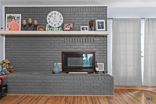 1003 Tyler Dr, Copperas Cove, TX 76522 - detailed view of wood finished floors, a brick fireplace, and a textured ceiling