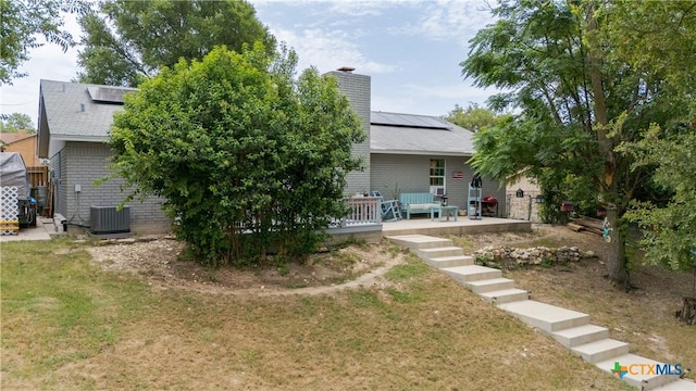 1003 Tyler Dr, Copperas Cove, TX 76522 - back of house featuring roof mounted solar panels, a lawn, a chimney, and brick siding