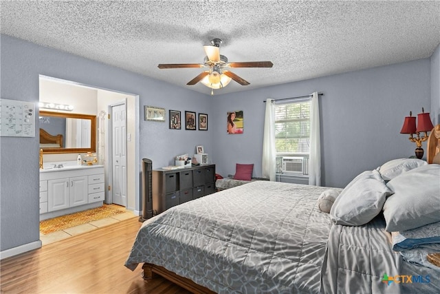1003 Tyler Dr, Copperas Cove, TX 76522 - bedroom with light wood finished floors, cooling unit, ensuite bathroom, a textured ceiling, and ceiling fan