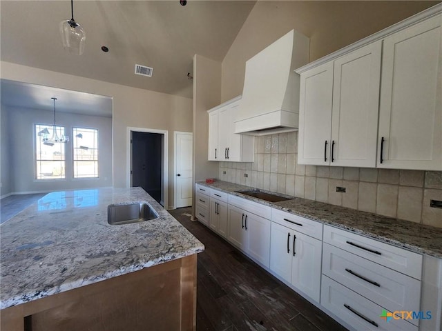 kitchen with premium range hood, sink, decorative backsplash, decorative light fixtures, and white cabinetry