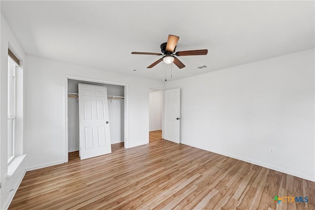 unfurnished bedroom featuring light wood finished floors, a closet, baseboards, and a ceiling fan