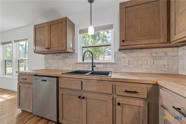 kitchen featuring wooden counters, dishwasher, a sink, and decorative backsplash