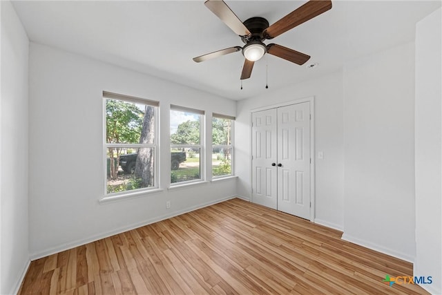 unfurnished bedroom featuring light wood-style floors, baseboards, and a closet