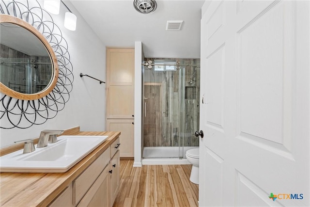 full bath featuring a shower stall, toilet, wood finished floors, and vanity