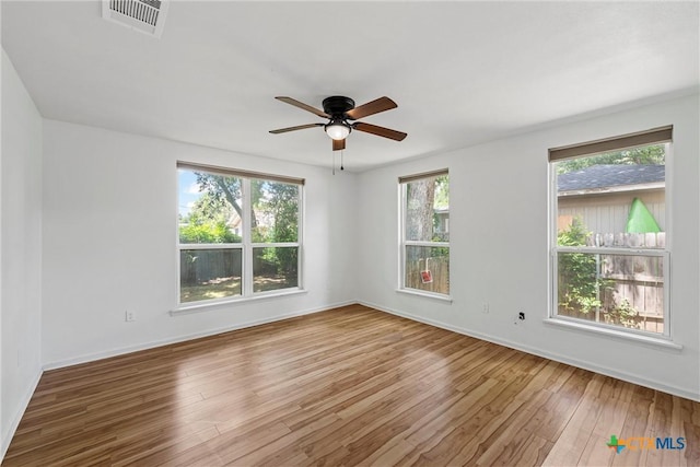 unfurnished room with wood finished floors, a ceiling fan, and baseboards