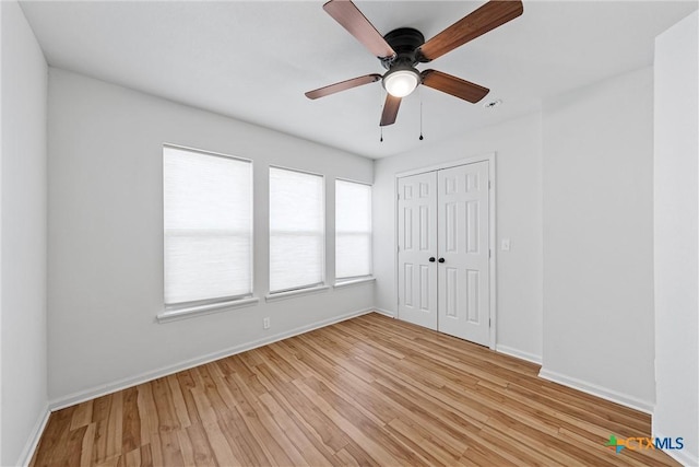 unfurnished bedroom featuring light wood finished floors, baseboards, a closet, and a ceiling fan