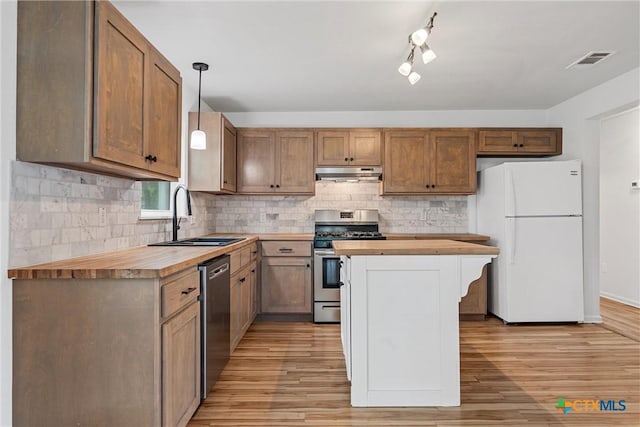 kitchen featuring appliances with stainless steel finishes, wooden counters, a sink, under cabinet range hood, and light wood-style floors
