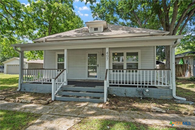 bungalow featuring covered porch, roof with shingles, and an outdoor structure