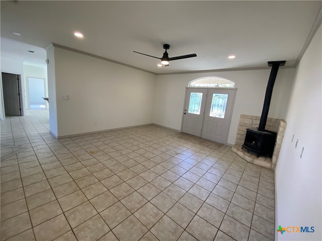 tiled foyer entrance with a wood stove, ceiling fan, and ornamental molding