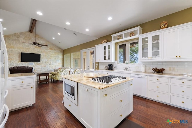 kitchen featuring backsplash, a sink, white cabinets, open floor plan, and white appliances