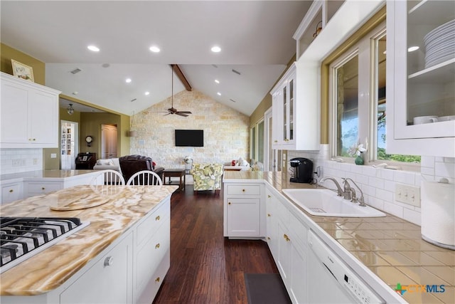 kitchen featuring white dishwasher, ceiling fan, a sink, open floor plan, and vaulted ceiling with beams