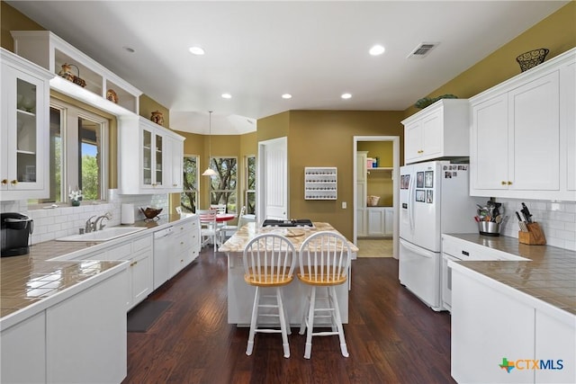kitchen with a kitchen island, a sink, white appliances, white cabinetry, and dark wood-type flooring