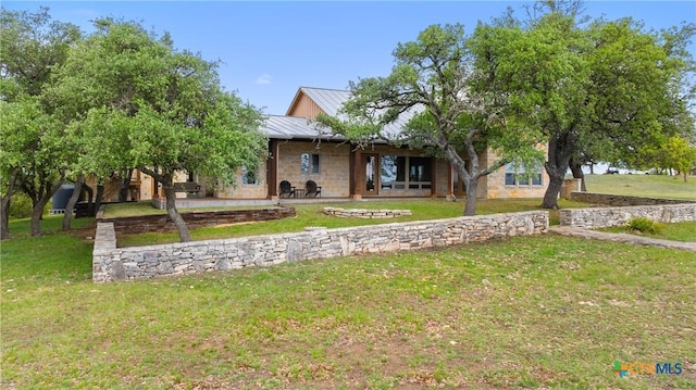 view of front of property featuring a standing seam roof, metal roof, a patio area, and a front lawn