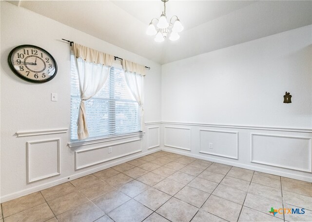 empty room with an inviting chandelier and light tile patterned flooring