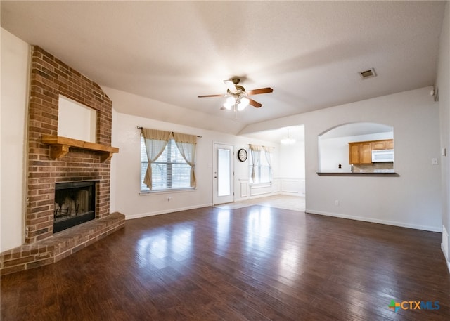 unfurnished living room with a brick fireplace, dark hardwood / wood-style floors, a textured ceiling, and ceiling fan