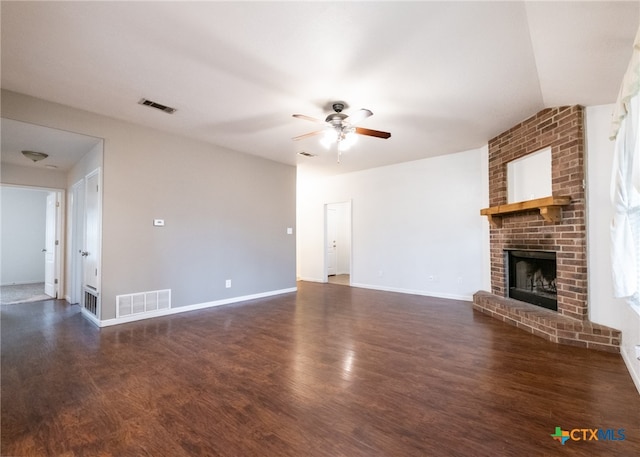 unfurnished living room featuring a brick fireplace, dark hardwood / wood-style floors, and ceiling fan